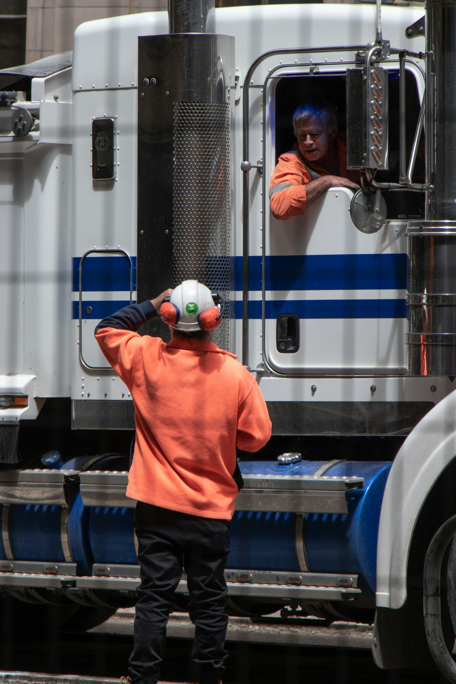 Driver leaning from the cab of a blue truck