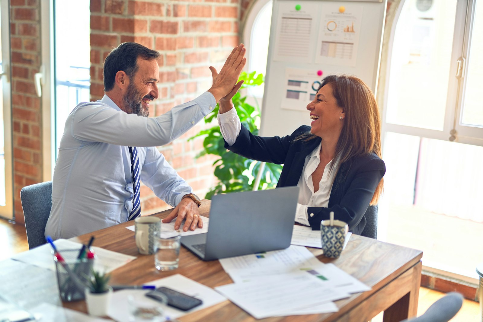 Two colleagues celebrating a win at a desk