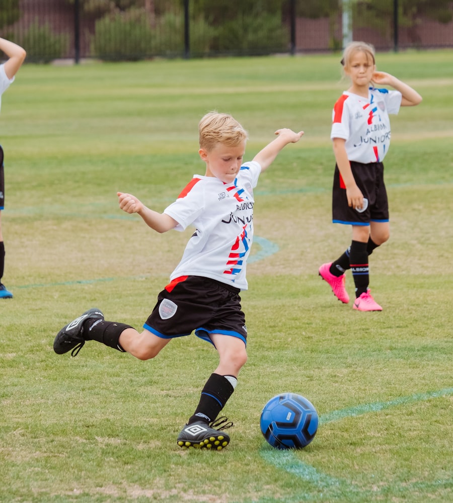 Kids in white jerseys playing a soccer match on grass