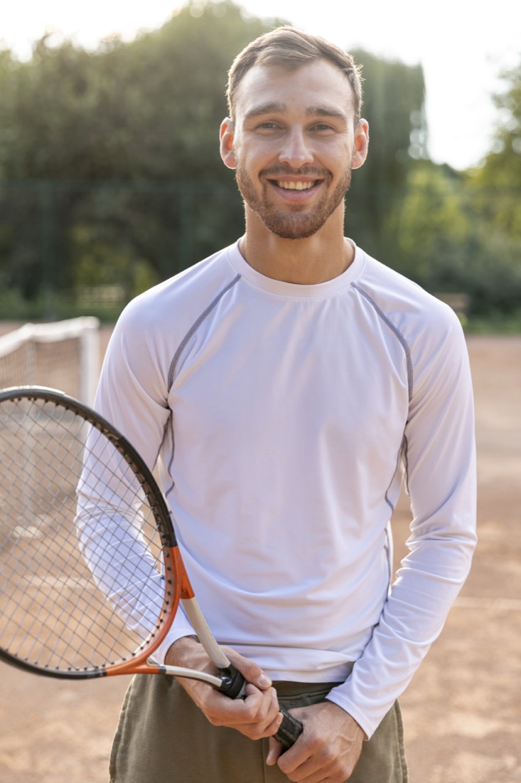 Tennis coach smiling on an outdoor court