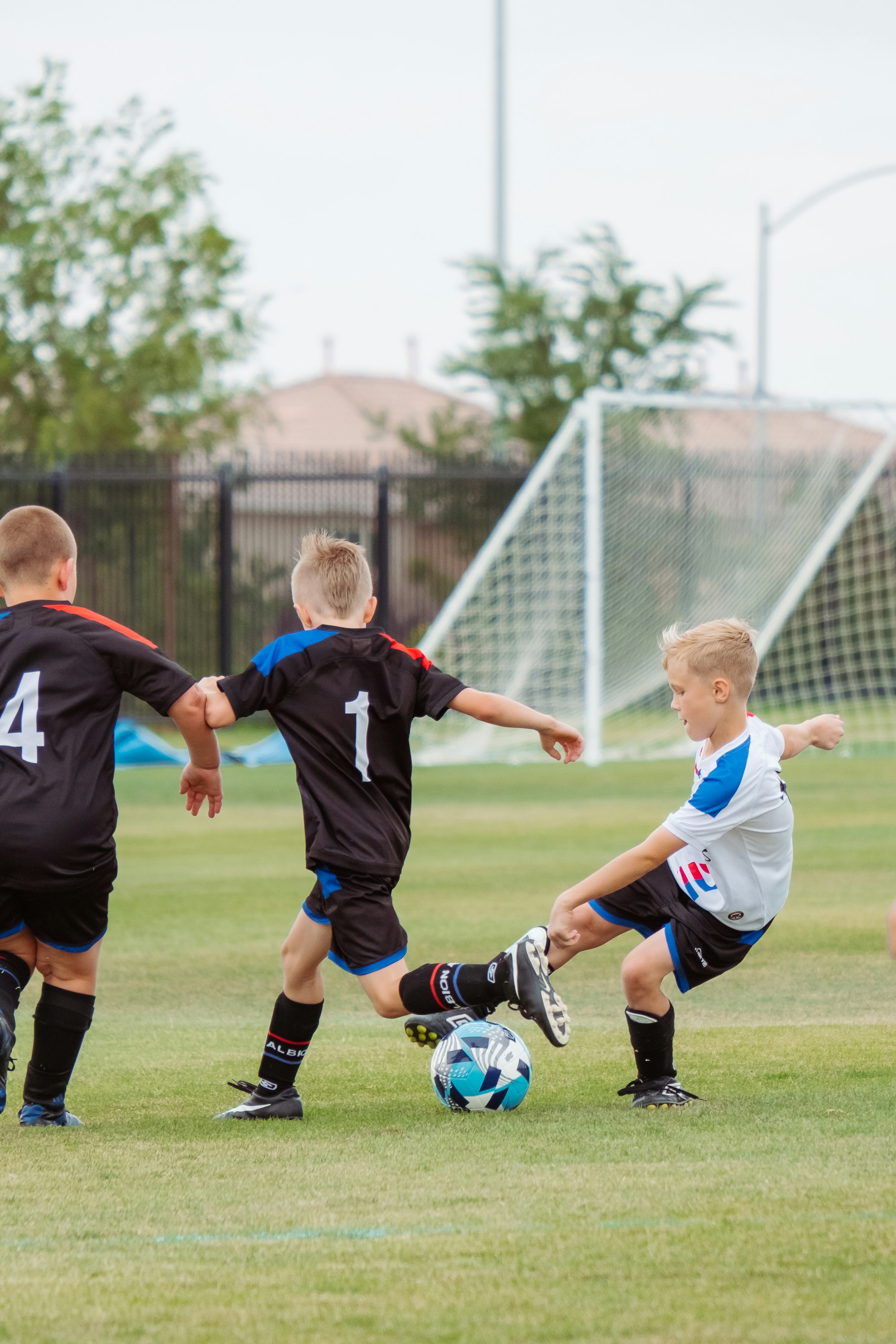 Kids in team jerseys chasing the ball during a junior soccer match