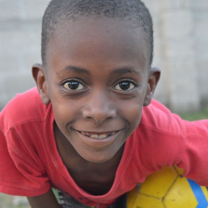 Smiling boy resting on a soccer ball