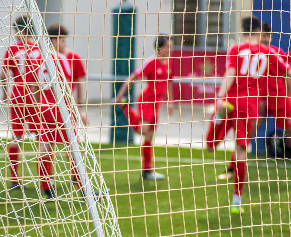 Young players in red jerseys celebrating near the goal