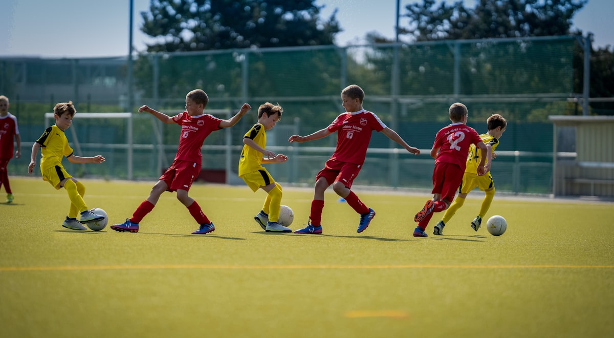 Kids in red and yellow kits playing a soccer scrimmage