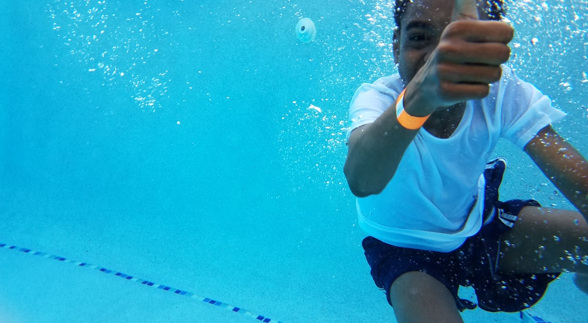 Child swimming underwater giving a thumbs up