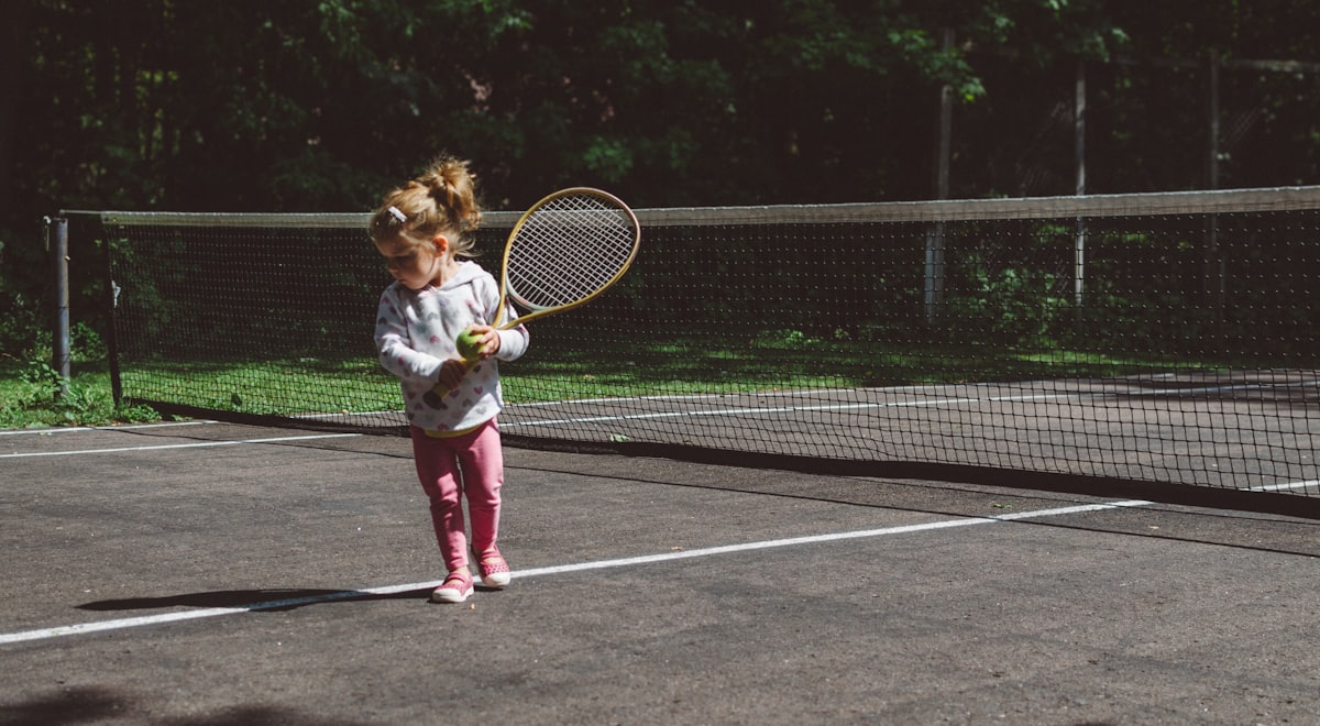 Young girl practicing her swing on an outdoor tennis court